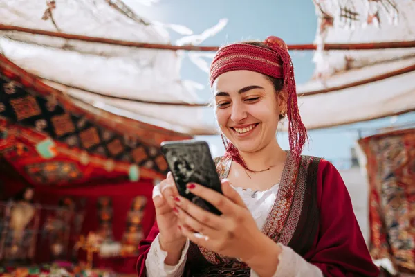 KOKOZINO Mobile Casino — Play anytime, anywhere A player using their smartphone during a festive local event, representing KOKOZINO’s fully mobile-friendly casino.